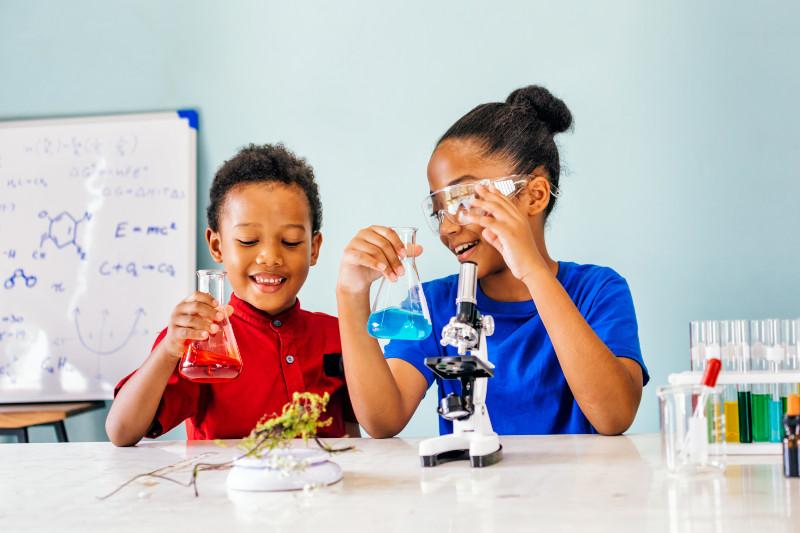 two children using science beakers and microscopes