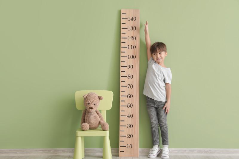 a child standing next to and reaching up to an oversized ruler