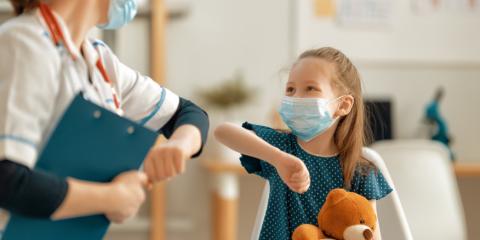 a girl and a pediatrician in masks elbow bumping