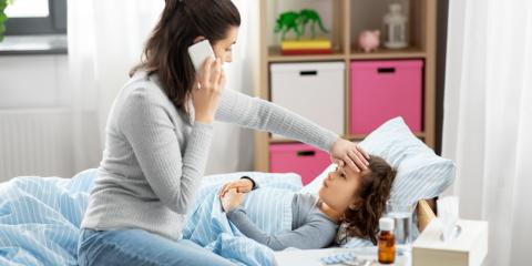 a mother using a phone while her daughter is sick in bed